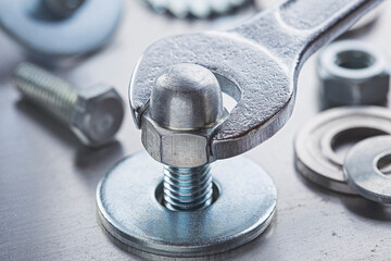 Wrench tightens steel cap nut in steel billet. Spanner, bolt, screw and nuts.