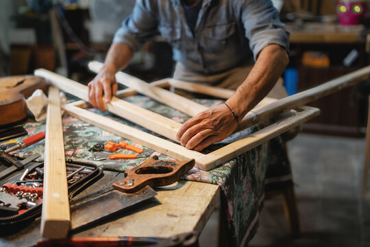 A carpenter builds a wooden frame on the workbench in the carpentry shop - crop shot - closeup on hands