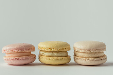Set of multicolored macaroons lined in a row on the white background. Traditional French dessert. St Valentine's Day. Yellow, beige and pink macaroons