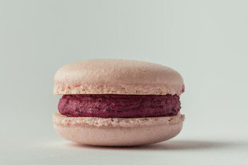 Pink strawberry macaroon with berry ganache fillig on the white background. Making traditional French dessert. Close up shot.  Macro shot. White background