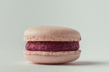 Pink strawberry macaroon with berry ganache fillig on the white background. Making traditional...