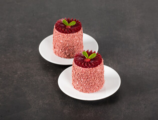 Modern dessert. Plum mousse cream cake of cylindrical shape with plisse jelly on top, on a plate....