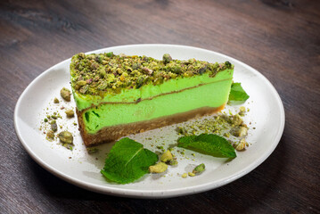 Pistachio cheesecake portion with matcha flavor and mint. A bright green piece of dessert on a plate.