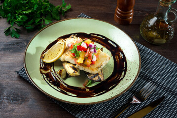 Cod fillet with salsa sauce and a slice of lemon on grilled eggplant halves.