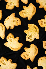 Closeup above view of baked ghost shaped butter cookies on black Halloween cookies - 538659628
