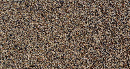 Texture of coarse sea sand close-up, small pebbles. For design, background, postcards, collages and compositions