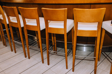 Wooden vintage chairs stand in a row indoors.
