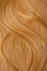 Red hair close-up as a background. Women's long orange hair. Beautifully styled wavy shiny curls. Hair coloring bright shades. Hairdressing procedures, extension.