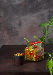Pickled green and red chili peppers on a dark table and dark background