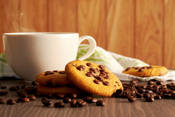 Coffee mug with hot steam, chocolate cookies and napkin