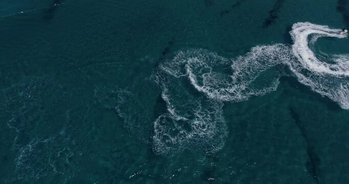 Aerial Top Down View Shot of a Person Jet Skiing in Circles. Beautiful Blue Oceanic Waters and Sun is Shining. 