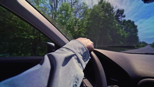 Female hand on the steering wheel of a car. Focus on the hand wide view. Travelling by SUV vehicle. Family car trip. Bumpy country road.