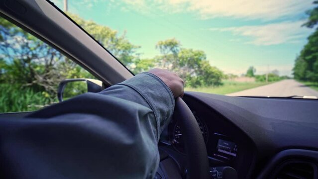 Close up of woman's hands on vehicle steering wheel while she driving. Focus on the hand wide view. Female driving a car in the bumpy rural area. Hands move on the wheel.