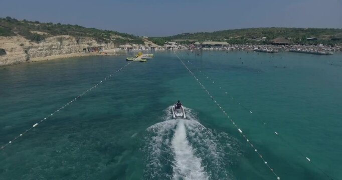 Aerial Top Down View Shot of a Person Jet Skiing in Circles. Beautiful Blue Oceanic Waters and Sun is Shining. 