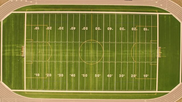 Imitation of the sport ball kicked and flying up fast. Fast speed ascending aerial top down view of empty soccer field without players. Football field with grass and white paint lines and marks.