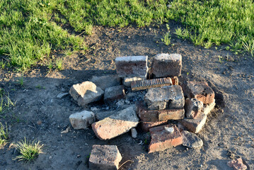 A summer campfire with bricks in a field at a campsite.