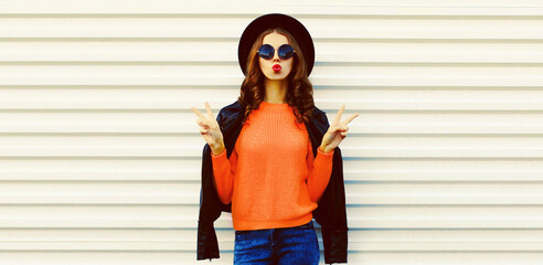 Fashionable portrait of stylish young woman model blowing her lips sending sweet air kiss wearing...