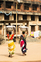 Two Indian women carrying a basket of fish on their head 