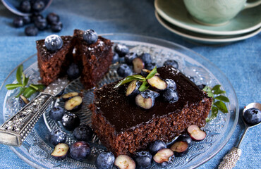 brownie auf glasteller mit blaubeeren und kaffetasse