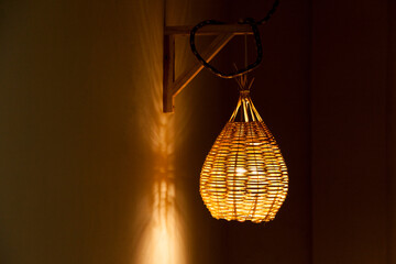 Pendant luminaire for outdoor area with yellow light. Handmade lamp made of straw. Luminaire concept. Home sweet home concept.