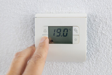 Thermostat is manually lowered to a temperature of 19 degrees Celsius. - obrazy, fototapety, plakaty