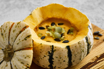 Pumpkin cream soup served in a squash with seeds