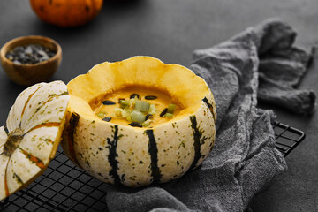 Pumpkin cream soup served in a squash with seeds