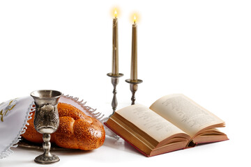 Challah bread covered with a special napkin, shabbat wine, torah and candles on white background....