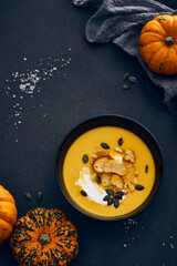 Pumpkin cream soup with croutons on dark background