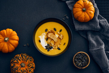 Pumpkin cream soup with seeds on dark background