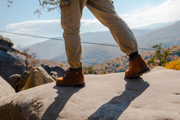 hiking concept men legs in boots on the rock