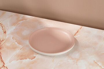 Empty pink blank plate on beige pink marble background. Minimalist mock up for product presentation.