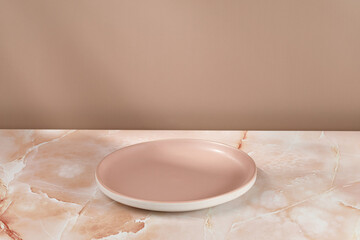 Empty pink blank plate on beige pink marble background. Minimalist mock up for product...