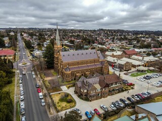 Aerial view of the Saints Mary and Joseph Catholic Cathedral in Armidale against a gray cloudy sky - Powered by Adobe