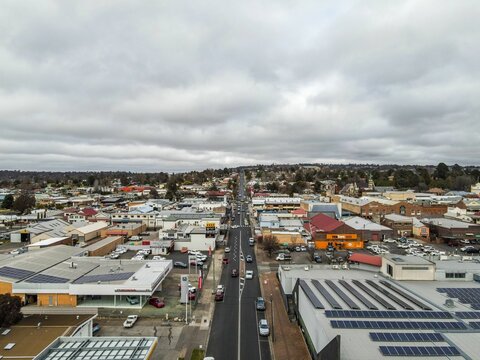 Aerial view of the town of Armidale with buildings and traffic on roads under a gray cloudy sky