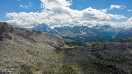 High rocks. Alps in Italy. South Tyrol. Dolomites. Green landscape with stones and green vegetation. Mountain landscape. Shooting from drone. Photo from a copter . Tourism.Blue clouds