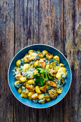 Roasted chicken nuggets, spinach, parmesan and noodles served on wooden table