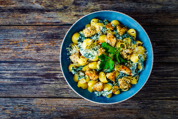 Roasted chicken nuggets, spinach, parmesan and noodles served on wooden table