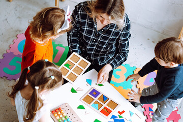 Development class for little children. Female teacher with children having fun and do smart puzzle...