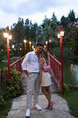Beautiful, romantic young couple on red bridge. Girlfriend, boyfriend, love and relationship concept.