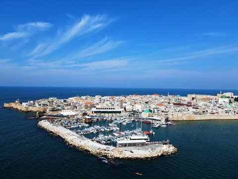 Aerial footage of the old City bay and Port of Acre, Israel by the sea under blue sky