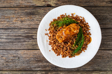 Stuffed meatball with mushrooms, buckwheat groats and pickled cucumbers on wooden table
