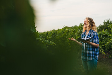 Curly-haired woman farmer holding pen and paper to collect data about vineyards problems in rural...