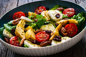 Fresh vegetable salad with cheese - camembert, artichoke, lettuce, cherry tomatoes, cucumber, ...