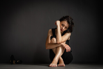 Fototapeta na wymiar young pretty girl sitting on the floor, pensive, thinking, depression, dark background, low key