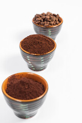 Three cups of coffee beans, ground coffee and cocoa for comparison.