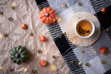 pumpkin with a cup of tea on a checkered plaid. autumn october decor. flat lay