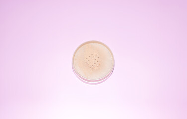 round package of loose powder on a pink background