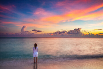 Fototapeta na wymiar Young woman looking at sunset over ocean on Maldives