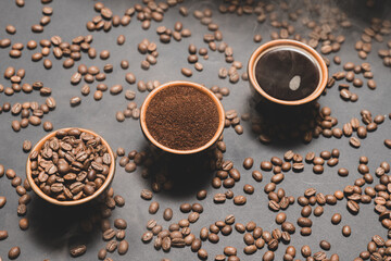 Three cups with different coffee, coffee beans, ground and ready-made drink.